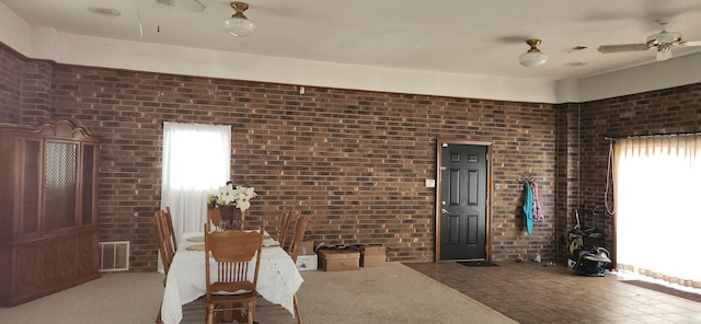 living room featuring ceiling fan and brick wall