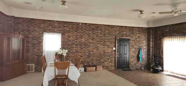 interior space featuring visible vents, brick wall, and a ceiling fan