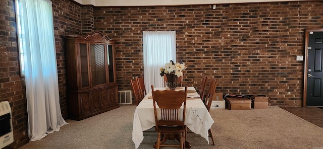 carpeted dining area featuring brick wall and heating unit