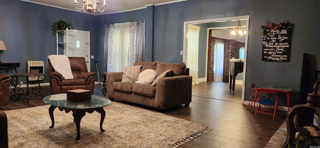 living area featuring a chandelier, crown molding, baseboards, and wood finished floors