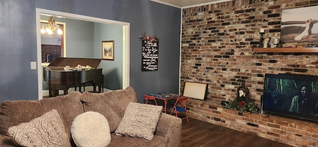 sitting room featuring a brick fireplace, a notable chandelier, wood finished floors, and brick wall