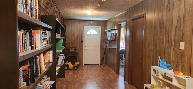 entrance foyer with wooden walls, wood finished floors, and a textured ceiling