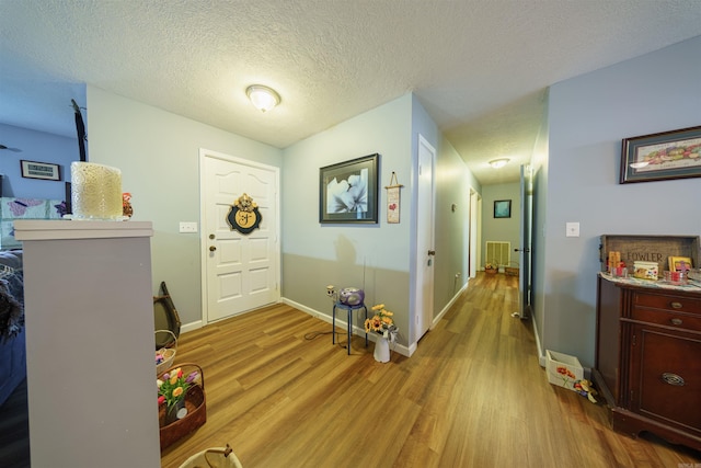 foyer with a textured ceiling and light hardwood / wood-style flooring