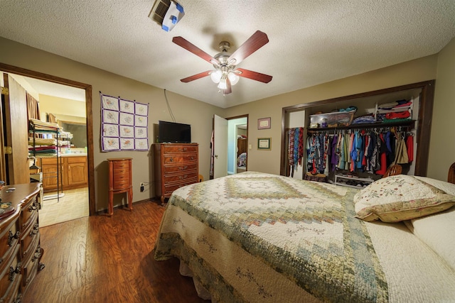 bedroom with dark wood-type flooring, a textured ceiling, ceiling fan, and a closet