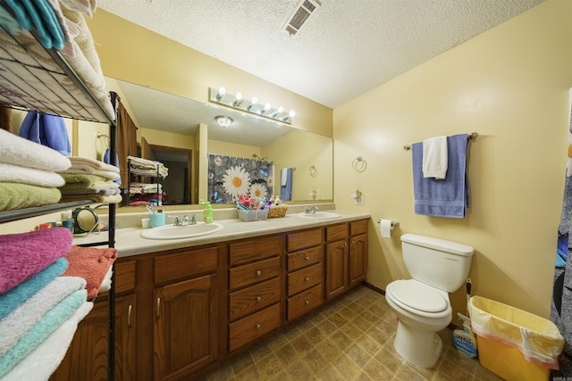 bathroom with toilet, a textured ceiling, and vanity