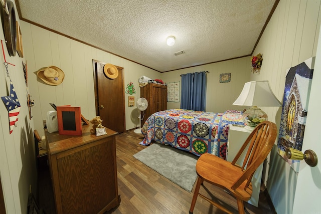 bedroom with dark hardwood / wood-style flooring, crown molding, and a textured ceiling