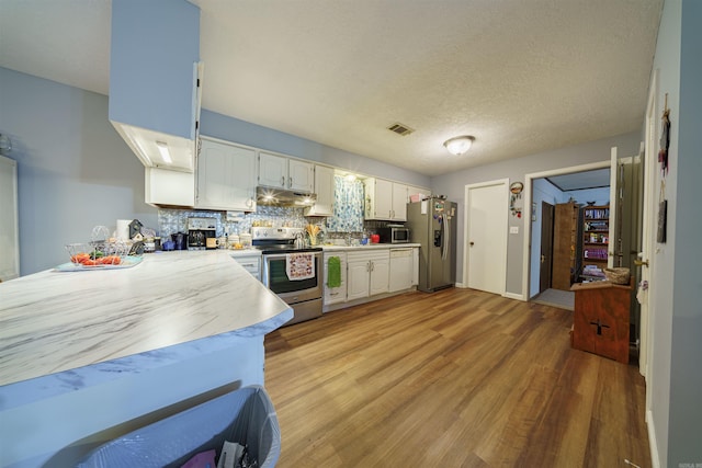 kitchen featuring a textured ceiling, light hardwood / wood-style flooring, stainless steel appliances, decorative backsplash, and white cabinetry