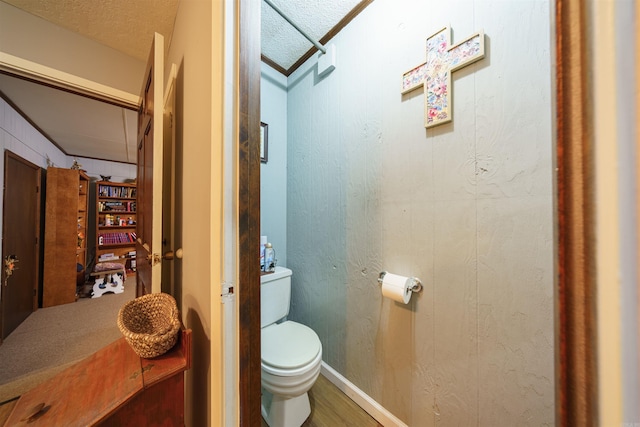 bathroom with ornamental molding, toilet, wood-type flooring, and a textured ceiling