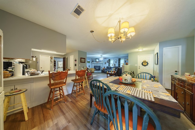 dining area featuring dark hardwood / wood-style flooring, an inviting chandelier, and a textured ceiling