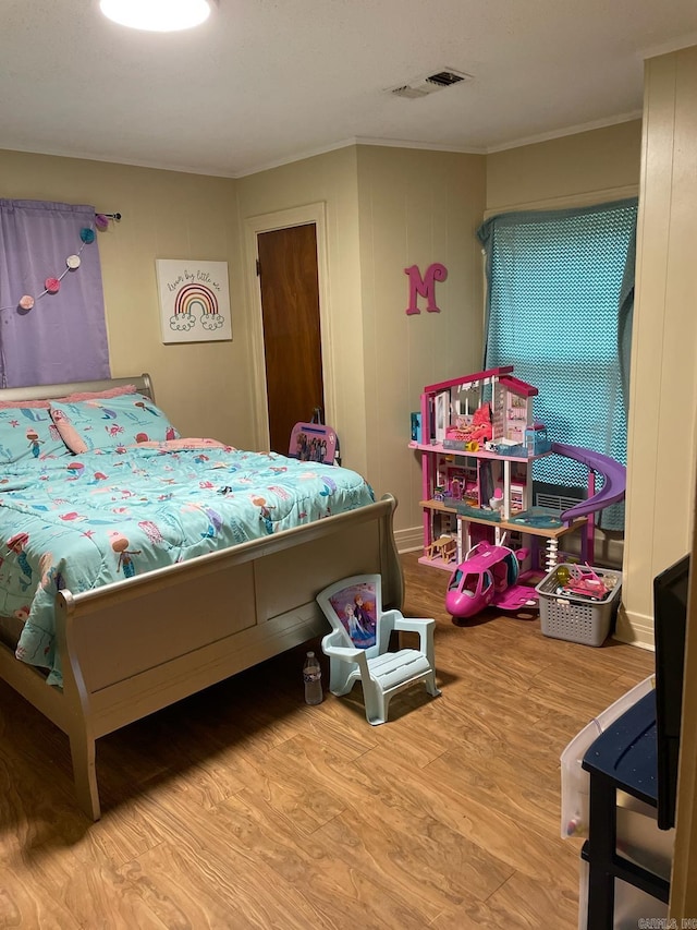 bedroom with crown molding and light wood-type flooring