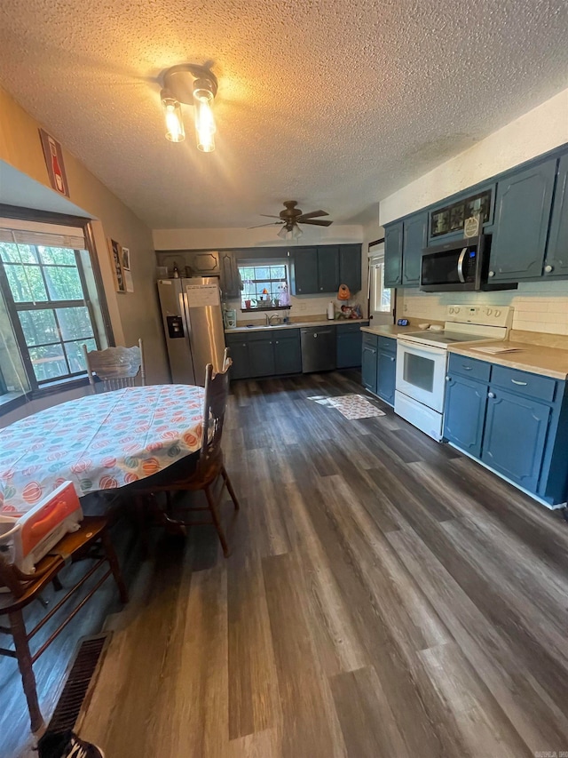 kitchen featuring ceiling fan, dark hardwood / wood-style floors, decorative backsplash, appliances with stainless steel finishes, and a textured ceiling