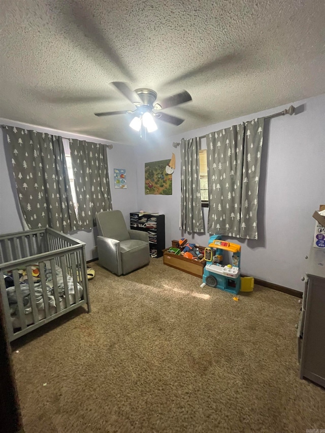 carpeted bedroom with ceiling fan, a textured ceiling, and a crib