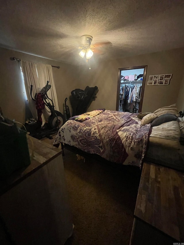 carpeted bedroom featuring ceiling fan, a textured ceiling, a closet, and a walk in closet