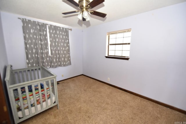 unfurnished bedroom with ceiling fan, carpet floors, and a crib