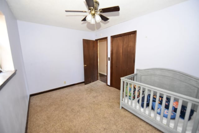 bedroom featuring ceiling fan, light colored carpet, and a nursery area