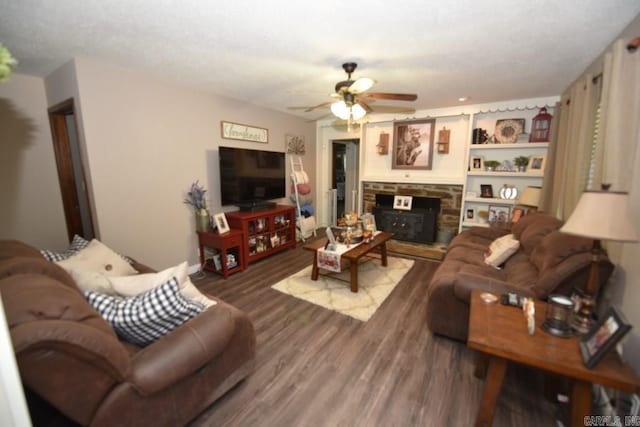 living room with ceiling fan, a textured ceiling, a wood stove, and hardwood / wood-style flooring