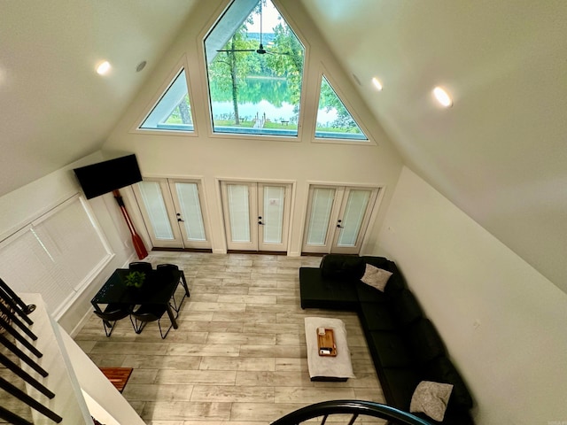 living room featuring french doors, high vaulted ceiling, and light wood-type flooring