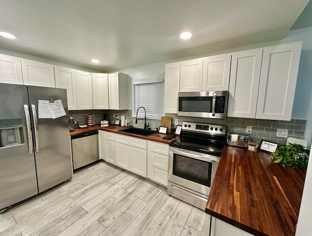 kitchen featuring white cabinetry, sink, butcher block counters, and stainless steel appliances