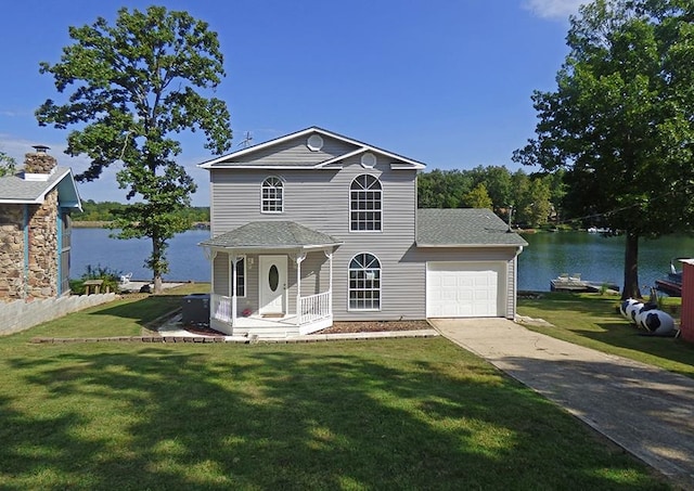 view of front of house with a garage, a water view, and a front lawn