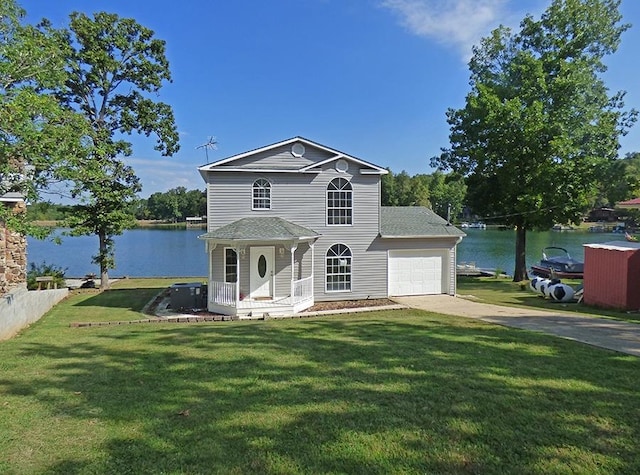 view of front of house with an attached garage, concrete driveway, a front yard, and a water view