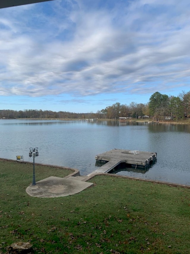 view of dock with a yard and a water view