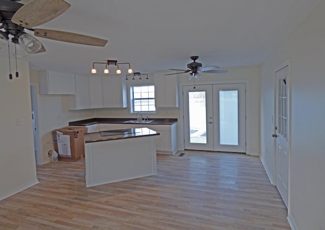 kitchen featuring a ceiling fan, a sink, a center island, french doors, and white cabinets