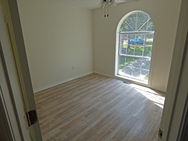 unfurnished room with visible vents, ceiling fan, baseboards, and wood finished floors