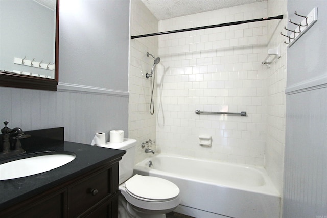 full bathroom with tiled shower / bath, toilet, a textured ceiling, and vanity