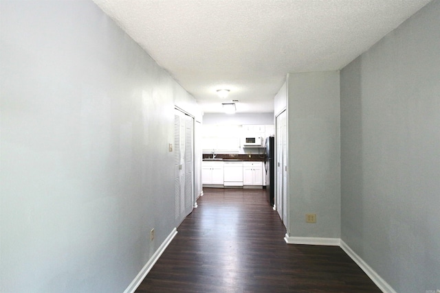 hall with dark wood-type flooring, sink, and a textured ceiling