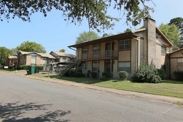 view of front of home with a balcony and a front yard