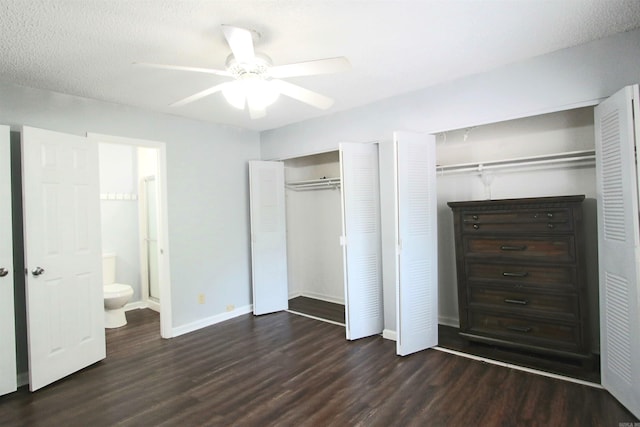 unfurnished bedroom featuring ensuite bath, multiple closets, dark hardwood / wood-style floors, ceiling fan, and a textured ceiling