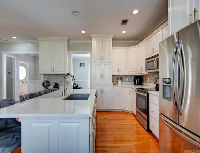 kitchen with a breakfast bar area, stainless steel appliances, white cabinetry, and sink