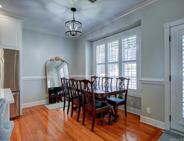 dining space featuring ornamental molding, wood-type flooring, and a chandelier