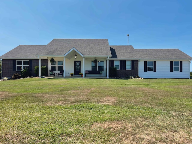 ranch-style home featuring brick siding, roof with shingles, covered porch, and a front lawn