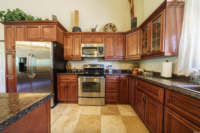 kitchen with appliances with stainless steel finishes and dark stone counters