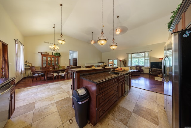 kitchen featuring vaulted ceiling, pendant lighting, light hardwood / wood-style floors, an island with sink, and stainless steel appliances