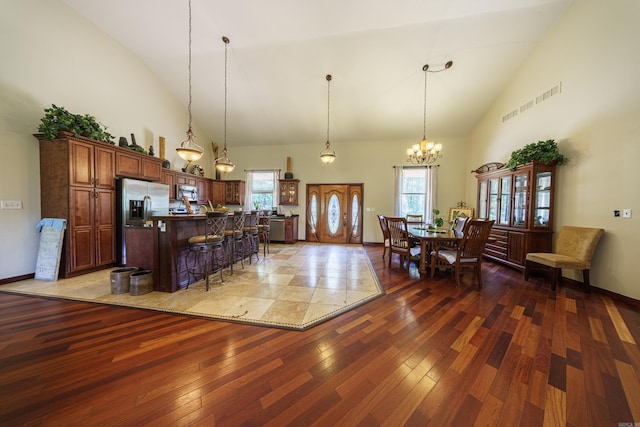 kitchen featuring a kitchen island, appliances with stainless steel finishes, dark wood-type flooring, a breakfast bar, and high vaulted ceiling