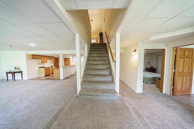 stairway featuring a paneled ceiling and carpet