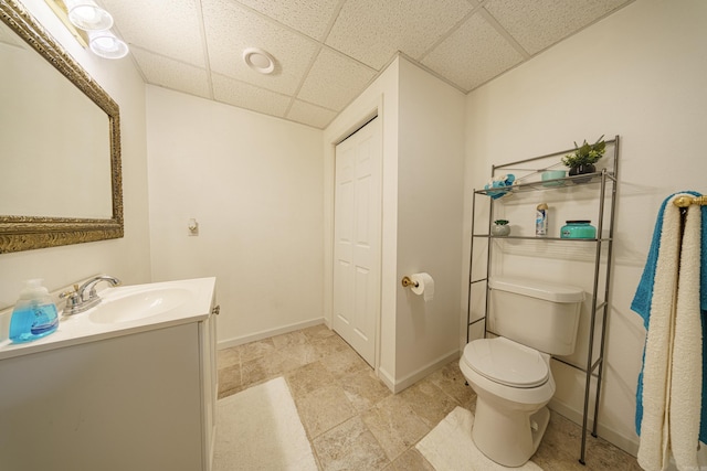 bathroom with vanity, toilet, and a drop ceiling