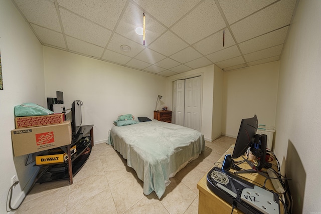 tiled bedroom featuring a paneled ceiling and a closet