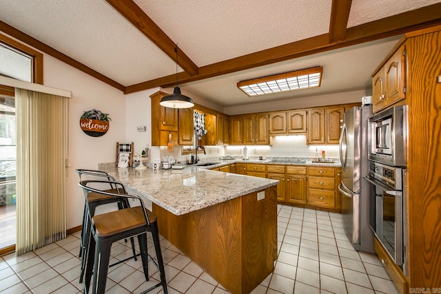 kitchen featuring hanging light fixtures, appliances with stainless steel finishes, light stone countertops, sink, and lofted ceiling