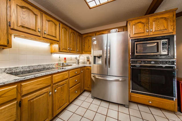 kitchen featuring black appliances, a textured ceiling, light stone counters, and tasteful backsplash