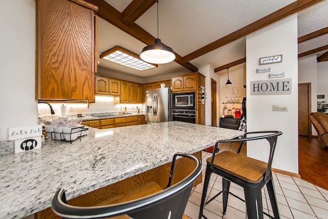 kitchen with a textured ceiling, pendant lighting, a breakfast bar, stainless steel appliances, and kitchen peninsula