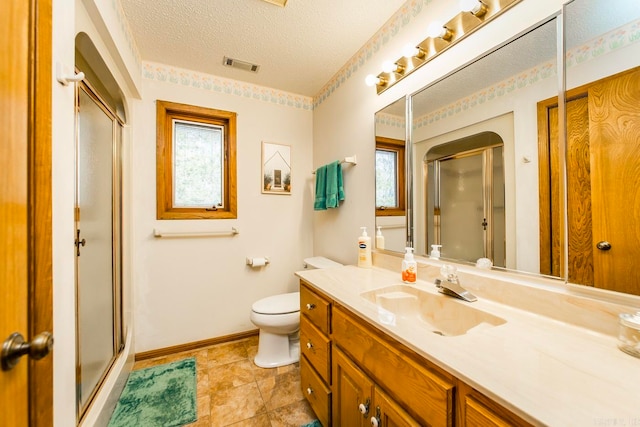 bathroom with vanity, toilet, a shower with shower door, and a textured ceiling