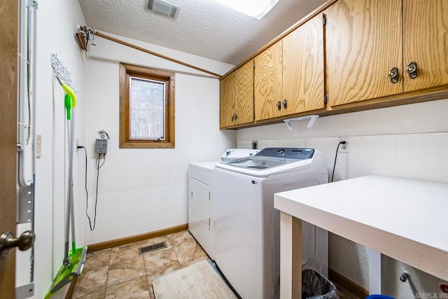 laundry area with washer and clothes dryer, cabinets, and a textured ceiling