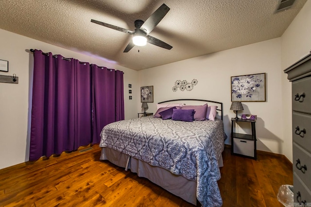 bedroom with dark hardwood / wood-style flooring, ceiling fan, and a textured ceiling