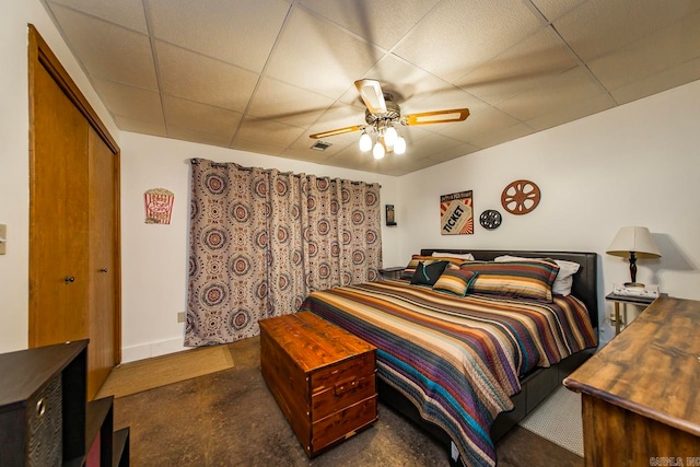 bedroom with a closet, ceiling fan, and a drop ceiling