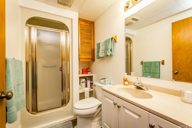 bathroom featuring a paneled ceiling, toilet, a shower with door, and vanity