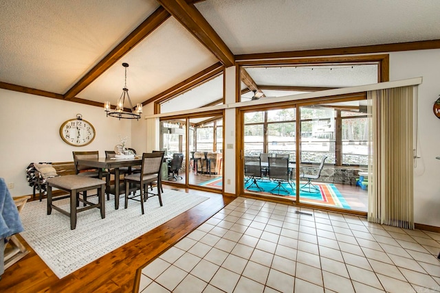 dining space with an inviting chandelier, vaulted ceiling with beams, light tile patterned floors, and a textured ceiling