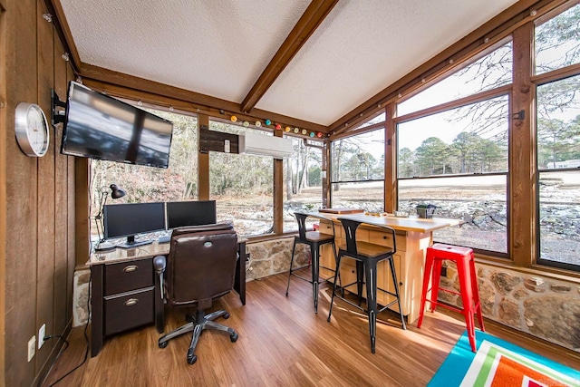 home office with a healthy amount of sunlight, vaulted ceiling with beams, wood walls, and hardwood / wood-style flooring